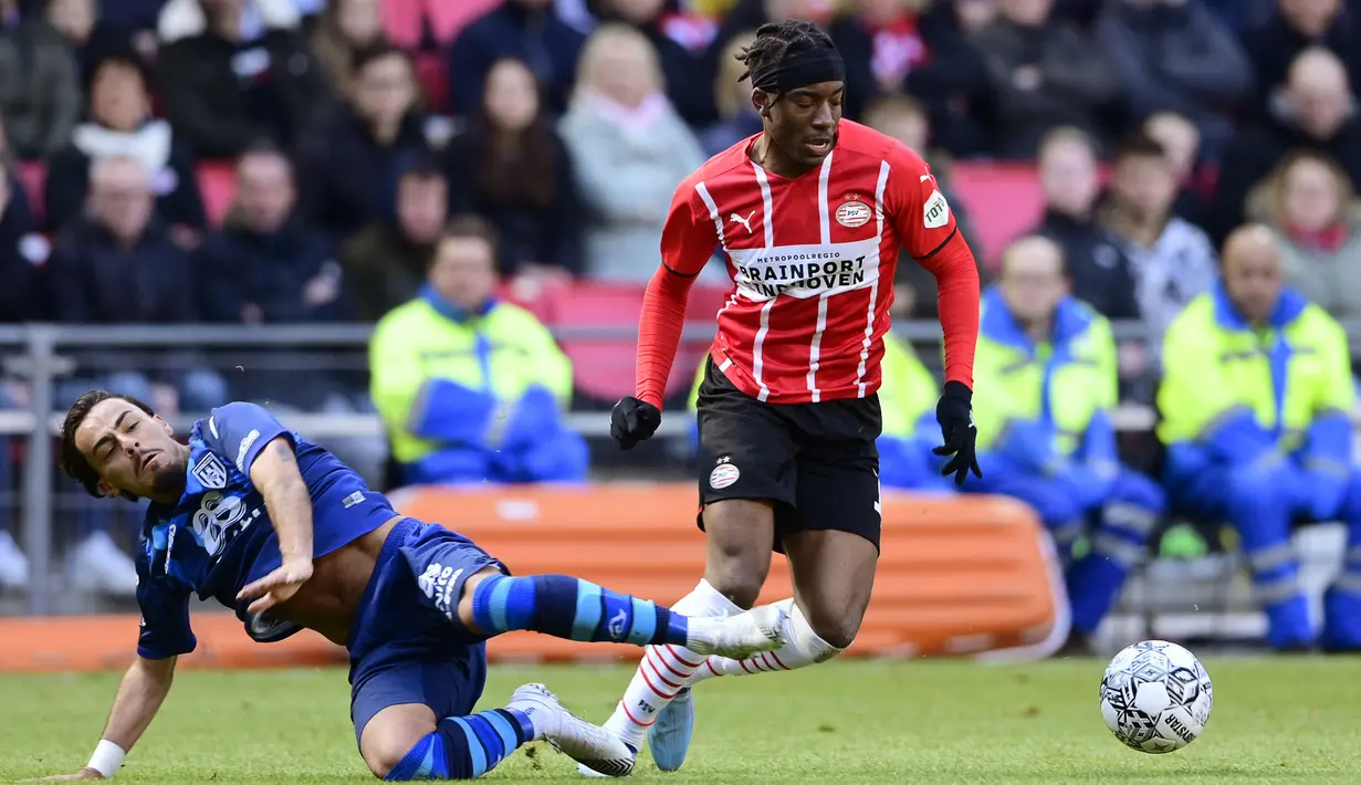 Pemain PSV Eidnhoven, Noni Madueke (kanan) berebut bola dengan pemain Heracles Almelo, Giacomo Quagliata pada laga lanjutan Liga Belanda 2022/2023 di Phillips Stadium, Eindhoven, 6 Maret 2022. Pada bursa transfer Januari 2023, Madueke direkrut Chelsea dengan harga 35 juta euro. (AFP/ANP/Olaf Kraak)