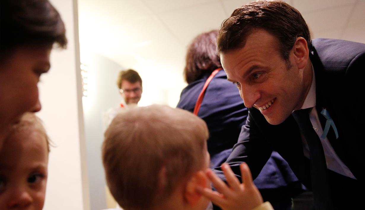 Presiden Prancis Emmanuel Macron berbicara dengan dengan anak-anak saat mengunjungi Graffiti's- Association Le Moulin Vert di Normandia, Prancis (5/4). (AP / Christophe Ena, Pool)
