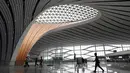 Para pekerja berjalan dalam Terminal Bandara Internasional Daxing Beijing, China, Selasa (9/7/2019). Bandara Internasional Daxing Beijing digadang-gadang akan menjadi yang terbesar di dunia. (GREG BAKER/AFP)