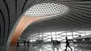 Para pekerja berjalan dalam Terminal Bandara Internasional Daxing Beijing, China, Selasa (9/7/2019). Bandara Internasional Daxing Beijing digadang-gadang akan menjadi yang terbesar di dunia. (GREG BAKER/AFP)