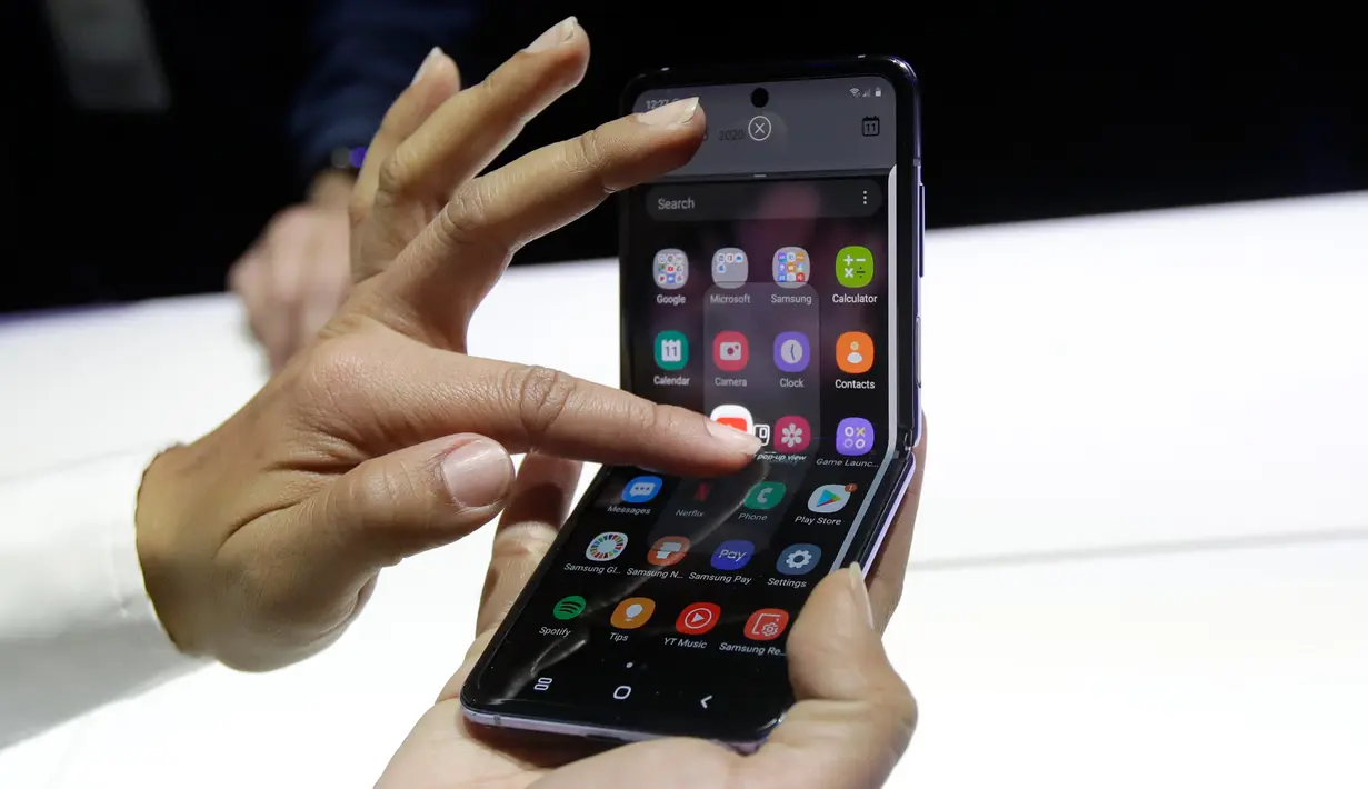 Seorang pekerja Samsung mendemonstrasi Galaxy Z Flip pada acara Unpacked 2020 di San Francisco, Selasa (11/2/2020). Menjadi perangkat kedua dengan layar lipat karyanya, Samsung menghadirkan perbedaan desain pada Galaxy Z Flip jika dibandingkan ponsel generasi pertama, Galaxy Fold. (AP/Jeff Chiu)