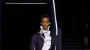 Kemeja transparan yang ringan kontras dengan mantel hitam tebal yang membentuk siluet tubuh. Jaket maskulin dipadukan dengan bustier, sementara coat tail dan kerah renda menjadi pelengkap yang menonjol.   [Dok/Dior],