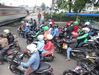 Kereta melintas di perlintasan kereta api yang tidak berpalang pintu di kawasan Roxy, Jakarta, Rabu (21/3). Pembukaan celah untuk akses sepeda motor di pintu perlintasan kereta api tersebut sangat membahayakan. (Liputan6.com/Arya Manggala)