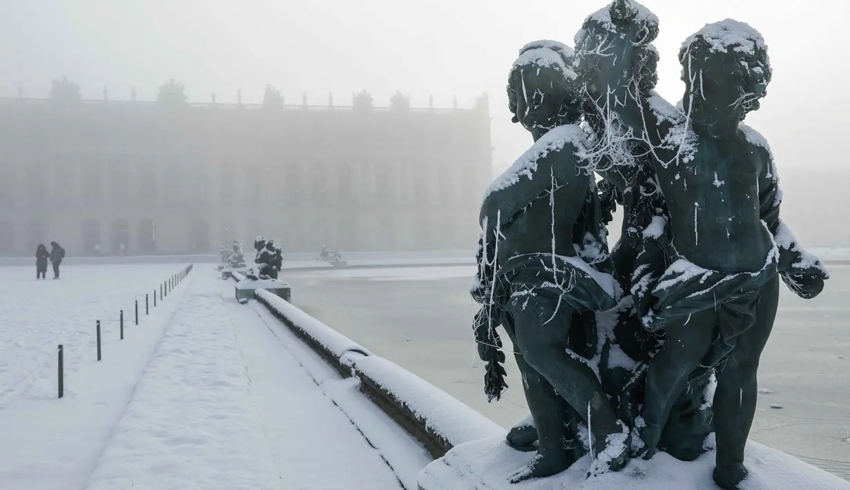 Sejauh ini, cuaca terdingin terjadi di Inggris, Prancis, dan Belanda. Tampak dalam foto, salju menyelimuti sebuah patung di tepi Midi bassin di taman Versailles, luar Kota Paris pada Selasa 6 Januari 2026. (GEOFFROY VAN DER HASSELT/AFP)