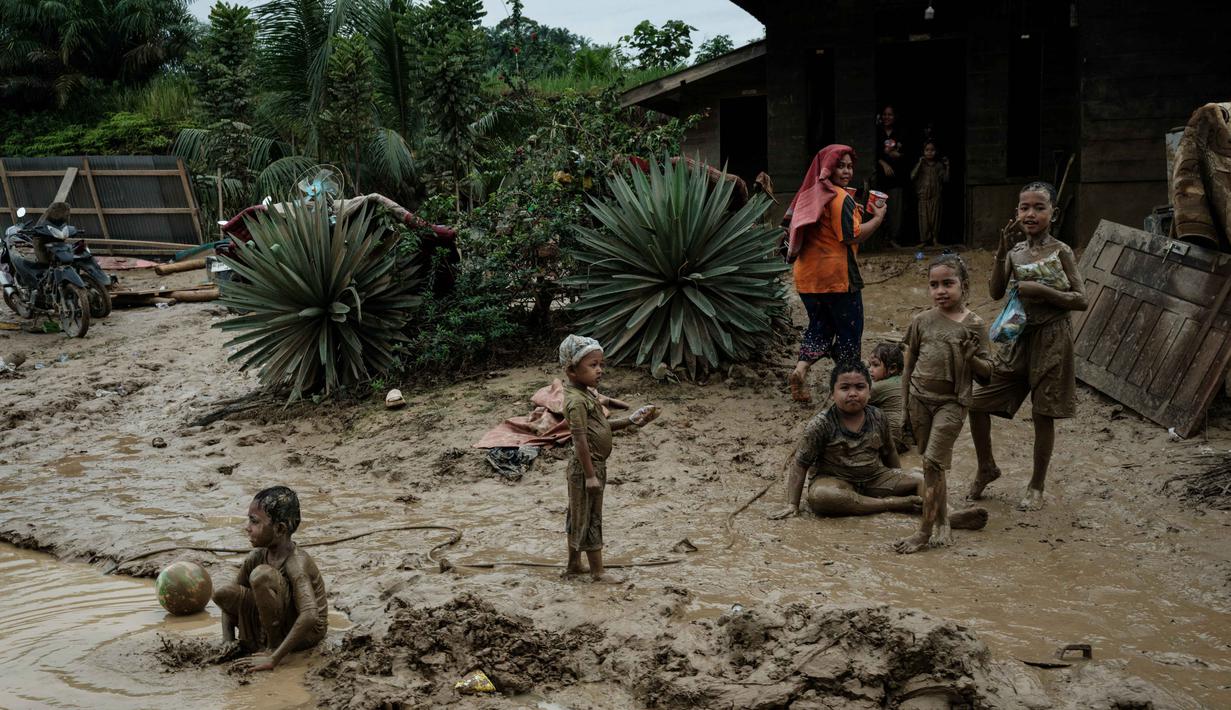 Kondisi lingkungan dan sanitasi yang kurang memadai pasca- bencana dapat memicu peningkatan kasus Infeksi Saluran Pernapasan Akut (ISPA), seperti batuk, pilek, hingga demam. Tampak dalam foto, anak-anak bermain di genangan lumpur di Pengidam, Aceh Tamiang, pada Senin 15 Desember 2025. (Yasuyoshi Chiba/AFP)