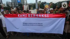 Massa dari Jamaah Muslimlin (Hizbulloh) melakukan aksi simpatik mengutuk pembakaran  Alquran di luar masjid utama Stockholm pada 28 Juni 2023 di kawasan Patung Kuda, Jakarta, Minggu (2/7/2023). Aksi dilakukan dengan menandatangani dukungan dan pembacaan kitab suci Alquran. (merdeka.com/Arie Basuki)