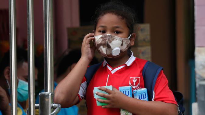 Seorang anak perempuan mengenakan masker meninggalkan sekolah saat polusi udara tingkat tinggi di Bangkok, Thailand (30/1). Polusi buruk dinilai tak sehat untuk seluruh masyarakat, khususnya anak-anak. (AP Photo/Sakchai Lalit)