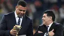 Mantan pemain Brasi, Ronaldo berbincang dengan mantan pemain Argentina, Diego Maradona saat menghadiri upacara kemenangan pertandingan final Piala Konfederasi 2017 antara Chile dan Jerman di Stadion Saint Petersburg, Rusia (2/7). (AFP Photo/Franck Fife)