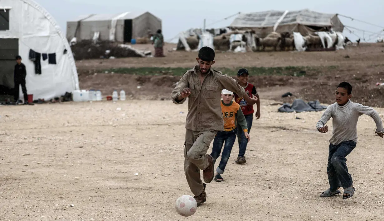 Seorang anak berusaha mengiring bola saat bermain sepak bola di sebuah kamp di al-Bil, timur dari kota Azas yang dikuasai pemberontak di Suriah utara (21/4). (AFP Photo/Sameer Al-Doumy)