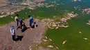 Sejumlah pria berdiri di tepi Sungai Salado di mana ikan mati menumpuk, Provinsi Buenos Aires, Argentina, 22 Januari 2023. (AP Photo/Natacha Pisarenko)