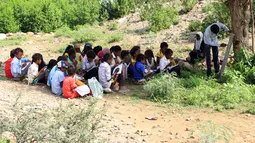 Para pelajar Yaman yang terlantar menghadiri kelas di bawah pohon sebuah lapangan terbuka, di distrik Abs utara, Yaman pada 28 Oktober 2018. UNICEF menyebut sekitar dua juta anak di Yaman putus sekolah, sejak konflik melanda pada 2015. (ESSA AHMED/AFP)