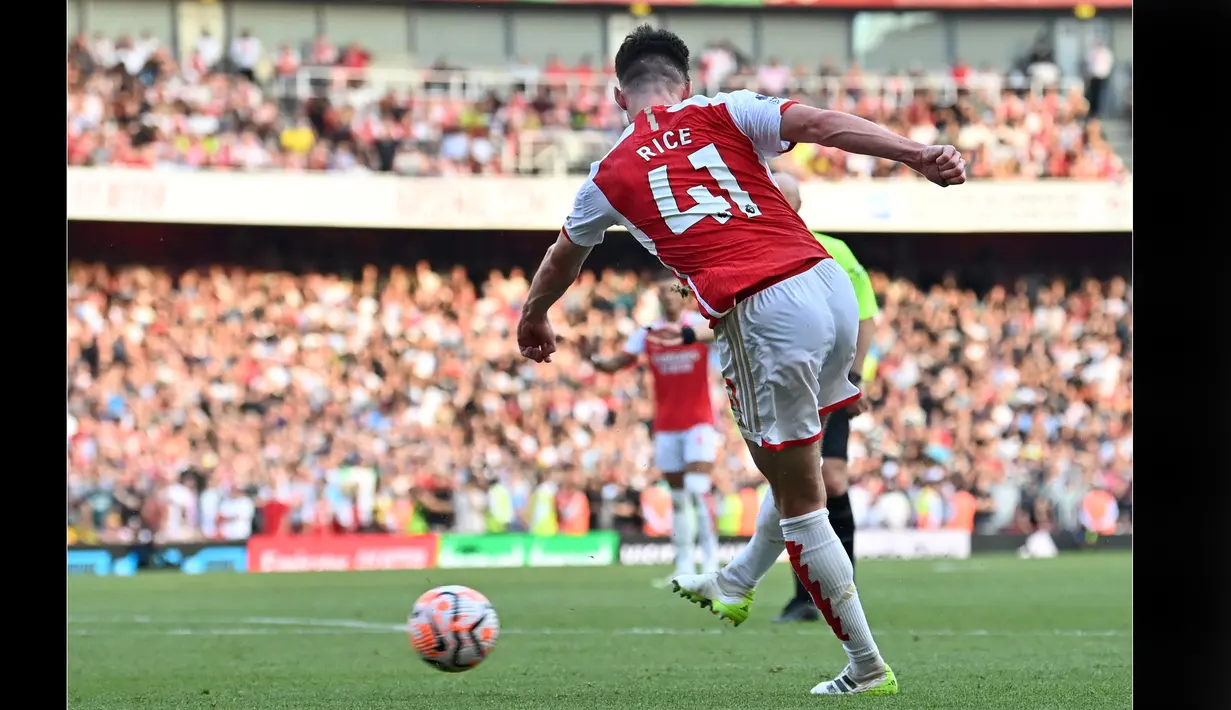 Pemain Arsenal, Declan Rice, menendang bola ke gawang MU dan membuahkan gol setelah memanfaatkan sepak pojok di babak tambahan waktu dan menjadi pahlawan kemenangan Arsenal dalam pertandingan pekan keempat Liga Inggris 2023/2024 yang berlangsung di Emirates Stadium, London, Senin (4/9/2023) dini hari WIB. (AFP/Glyn Kirk)