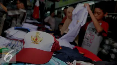 Calon pembeli melihat baju seragam yang dijual di Pasar Senen, Jakarta, Selasa (12/7). Penjualan seragam sekolah menjelang tahun ajaran baru mengalami peningkatan sekitar 30-50 persen dari hari biasa. (Liputan6.com/Gempur m Surya)