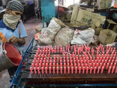 Seorang pekerja membuat lilin jelang Diwali atau Festival Cahaya di Ahmedabad, India, 25 Oktober 2021. Diwali adalah salah satu festival besar yang dirayakan oleh umat Hindu, Jain, Sikh dan beberapa umat Buddha, terutama umat Buddha Newar. (SAM PANTHAKY/AFP)