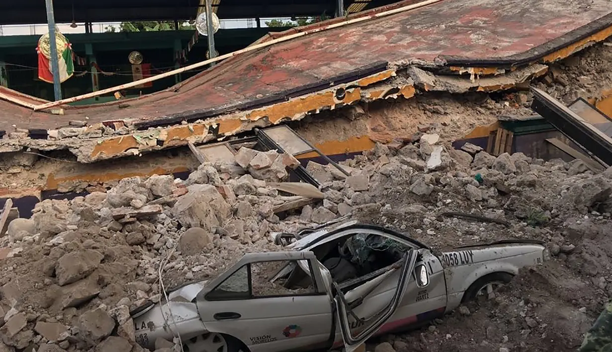 Sebuah mobil ringsek tertimpa reruntuhan bangunan yang ambruk akibat gempa 7,1 SR di Jojutla, negara bagian Morelos, Meksiko, Selasa (19/9). Ini merupakan gempa terkuat kedua yang mengguncang Meksiko dalam bulan ini. (AP Photo/Carlos Rodriguez)