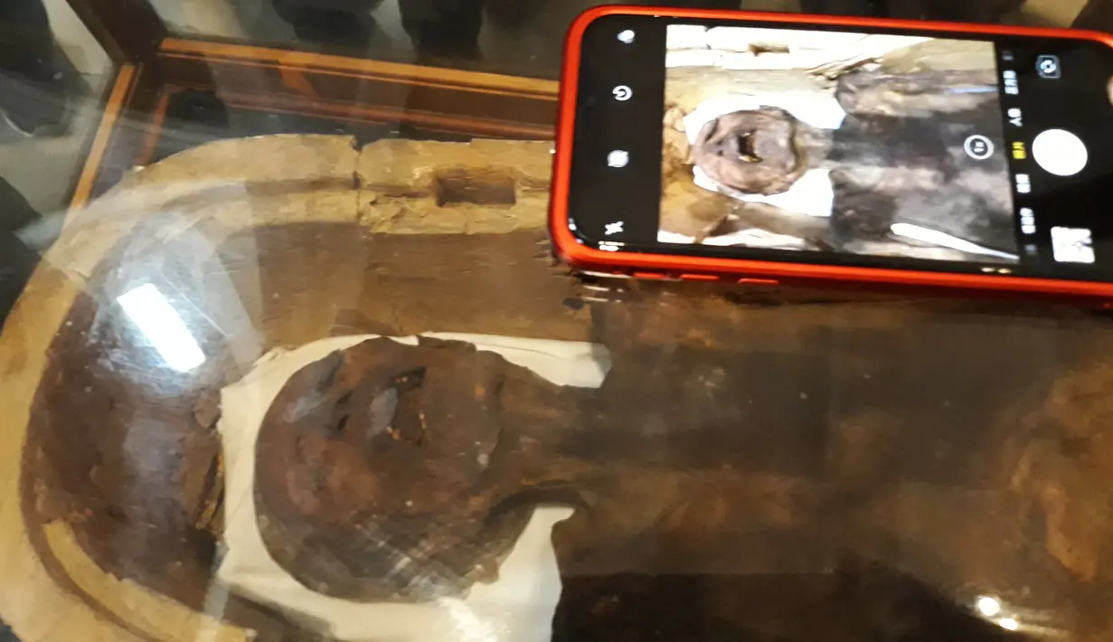Pengunjung mengabadikan gambar 'Mumi Menjerit' di Museum Mesir, Kairo, Selasa (14/2). Setelah bertahun-tahun berspekulasi, penelitian terbaru menunjukkan bahwa mumi tersebut adalah putra Raja Ramses III (Firaun dari dinasti ke-20). (KHALED DESOUKI/AFP)