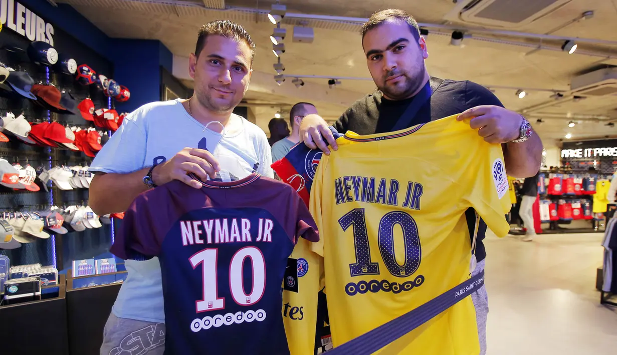 Dua orang fans menunjukan jersey pemain Paris Saint Germain, Neymar Jr, di toko merchandise di Paris, Jumat (4/8/2017). Setelah resmi bergabung dengan Paris Saint Germain, jersey Neymar Jr langsung diburu suporter klub Ibu kota. (AP/Michel Euler)