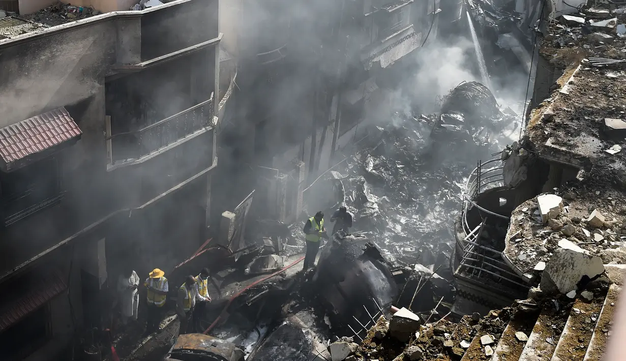 Petugas penyelamat berkumpul di lokasi jatuhnya pesawat Pakistan International Airlines di Karachi, Pakistan, Jumat (22/5/2020). Proses evakuasi baru berakhir pada Sabtu dini hari. (Rizwan TABASSUM/AFP)