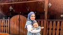 2. Nathalie kompak bersama baby Adzam mengenakan baju overall jeans dan inner warna putih. Gayanya dipadukan dengan hijab bermotif warna biru senada. (Instagram/nathalieholscher).