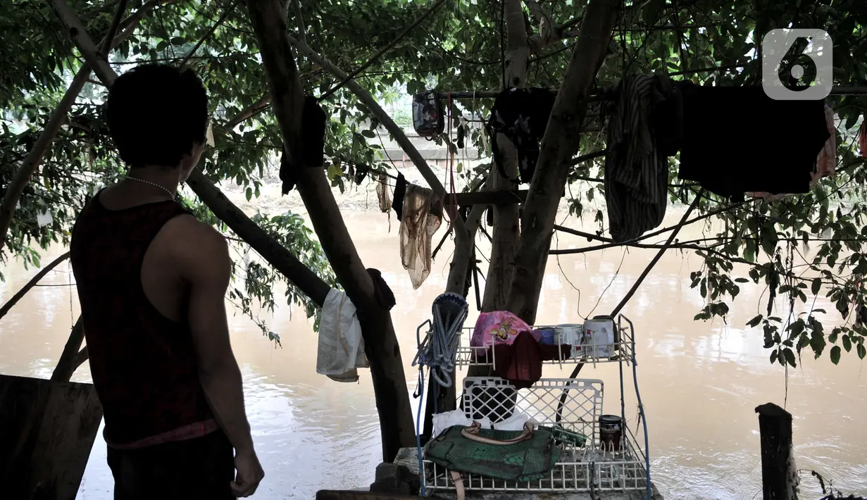 Salah seorang warga berdiri di pinggir bantaran kali usai banjir merendam gubuk miliknya yang berada di pinggir Kanal Banjir Barat (KBB), Jakarta, Rabu (8/1/2020). (merdeka.com/Iqbal S Nugroho)