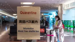 Seorang penumpang berjalan dengan kopernya di aula kedatangan di Bandara Internasional Haneda Tokyo, Jumat (18/2/2022). Pemerintah Jepang mengumumkan rencana untuk melonggarkan aturan perbatasan virus bagi pekerja dan pelajar. (AFP/Philip Fong)