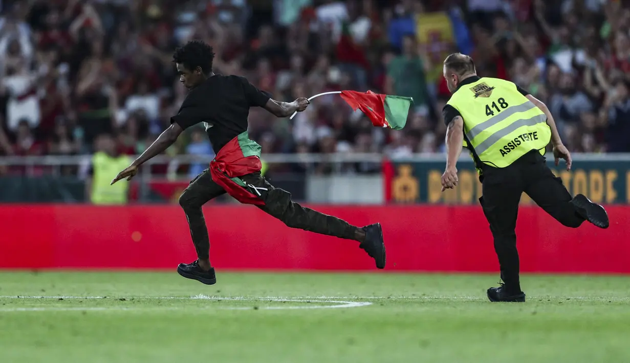 Seorang penyusup lapangan berlari menghindari kejaran petugas keamanan di tengah laga Grup J Kualifikasi Euro 2024 antara Timnas Portugal menghadapi Bosnia Herzegovina di Luz Stadum, Lisbon, Portugal, Minggu (18/6/2023) dini hari WIB. (AP Photo/Armando Franca)