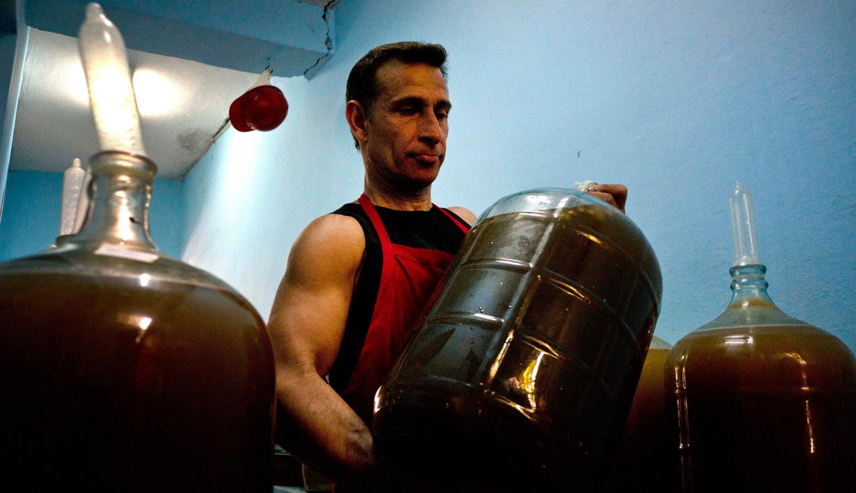 Kondom yang menutupi di mulut kendi berisikan air anggur tersebut, perlahan mengembang usai anggur melakukan fermentasi dan menghasilkan gas. (AP Photo)