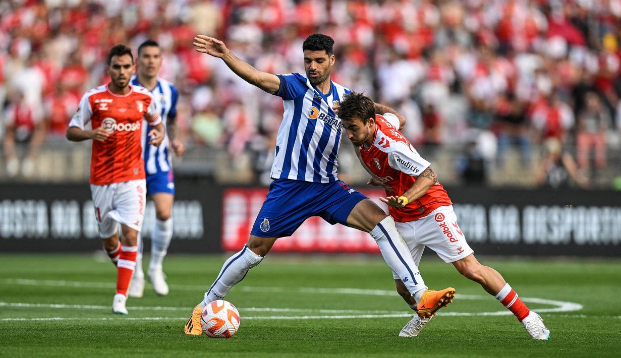 Pemain FC Porto, Mehdi Taremi (tengah) berebut bola dengan pemain SC Braga, Andre Horta pada laga Piala Liga Portugal (Taca de Portugal) di Stadion National Sports Center Jamor, Oeiras, 4 Juni 2023. Taremi dikabarkan menjadi salah satu incaran MU setelah berhasil tampil apik pada musim lalu. Ia tercatat sukses mencetak 31 gol dalam 51 penampilan di semua kompetisi untuk Porto. Kini, pemain berkebangsaan Iran tersebut memiliki harga 20 juta euro. (AFP/Patricia De Melo Moreira)