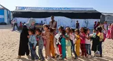 Guru-guru Palestina membariskan murid-murid di halaman sekolah yang didirikan oleh Asosiasi Kebudayaan Mayasem dengan dukungan UNICEF, sebelum pelajaran di kamp pengungsian di kawasan al-Qarara, Khan Yunis, di bagian selatan Jalur Gaza pada Selasa 7 Oktober 2025. (Omar AL-QATTAA/AFP)