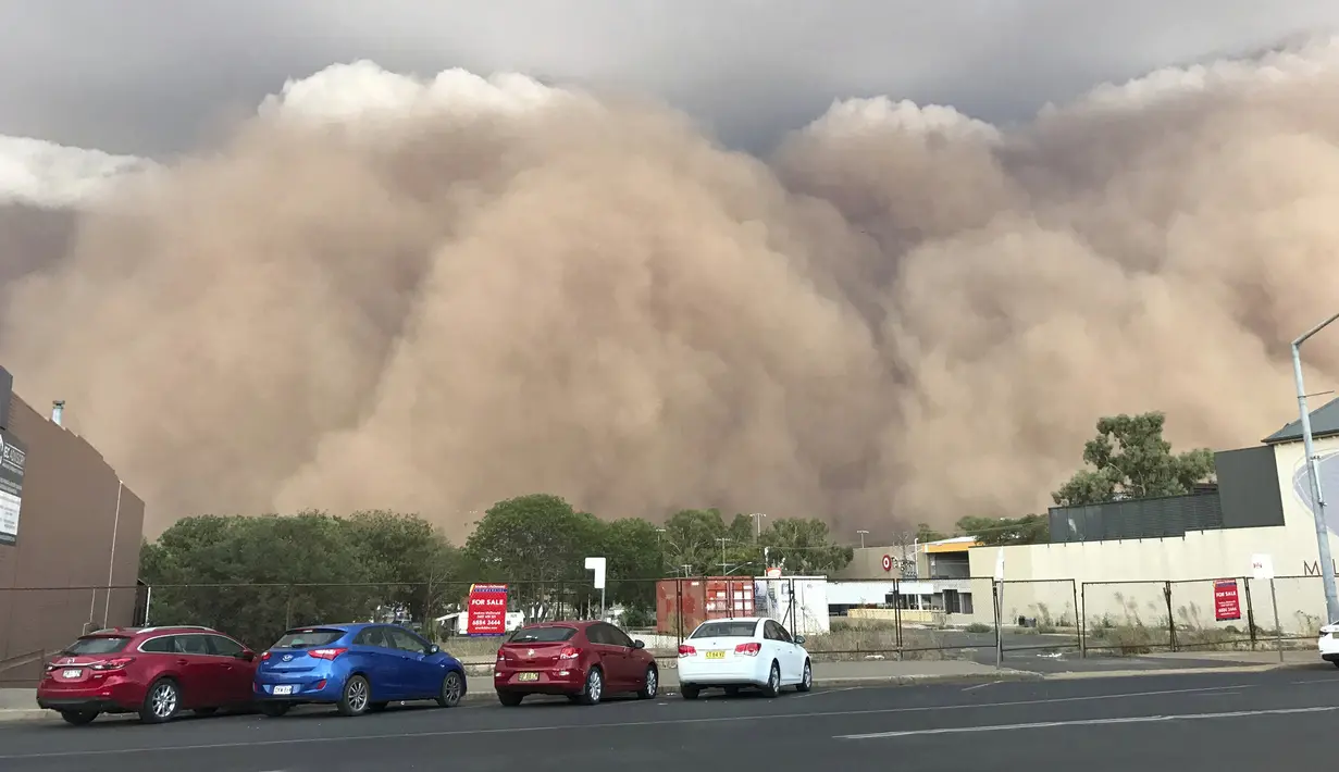 Sejumlah mobil terparkir saat badai debu mengepul di sebuah jalan di Dubbo, Australia, 400 km (248 mil) barat Sydney (19/1/2020). Hembusan angin 107 kilometer per jam (66 mph) dicatat di Dubbo saat badai debu turun ke atas kota. (Ian Harris via AP)