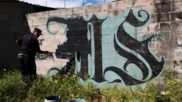 Polisi saat akan menghapus sebuah grafiti yang disuga kuat dibuat oleh geng Mara Salvatrucha di Mejicanos, El Salvador, (9/12). Kepolisian El Salvador sedang melakukan operasi untuk mencari keberadaan geng tersebut. (REUTERS/Jose Cabezas)