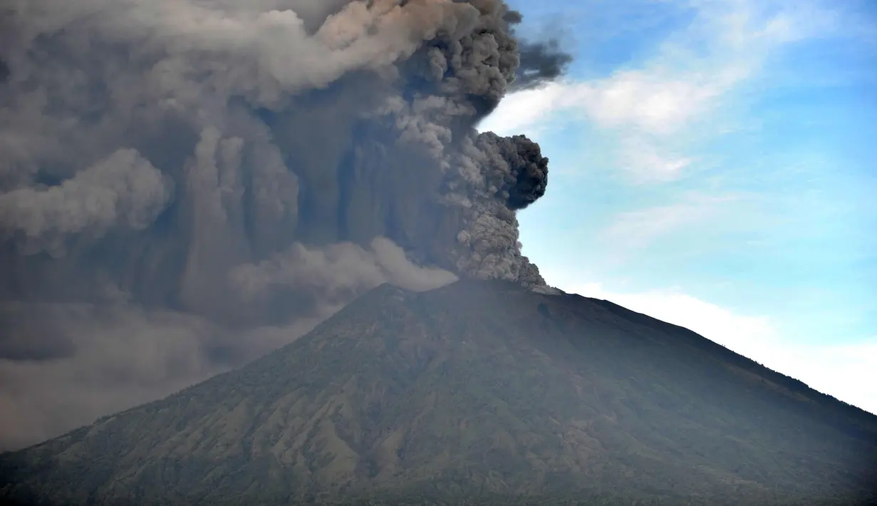 Semburan abu vulkanik Gunung Agung terlihat dari sebuah desa di Kecamatan Kubu, Karangasem, Bali, Minggu (26/11). Semburan asap dan abu vulkanik Gunung Agung mencapai ketinggian 1.500 meter dari puncak Gunung Agung. (AFP/Sonny Tumbelaka)