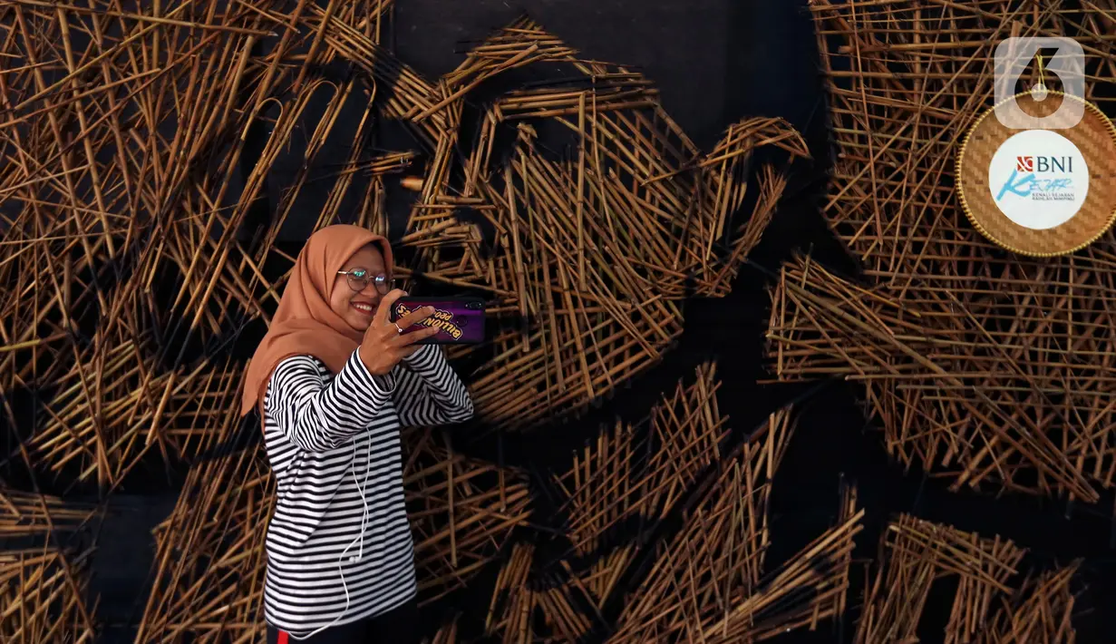 Pengunjung berswafoto di depan karya instalasi bambu berbentuk wajah Jenderal Sudirman karya Nus Salomo yang dipamerkan pada aksi Kenali Sejarah Raihlah Mimpimu di Terowongan Dukuh Atas, Jakarta, Minggu (24/11/2019). (Liputan6.com/Johan Tallo)