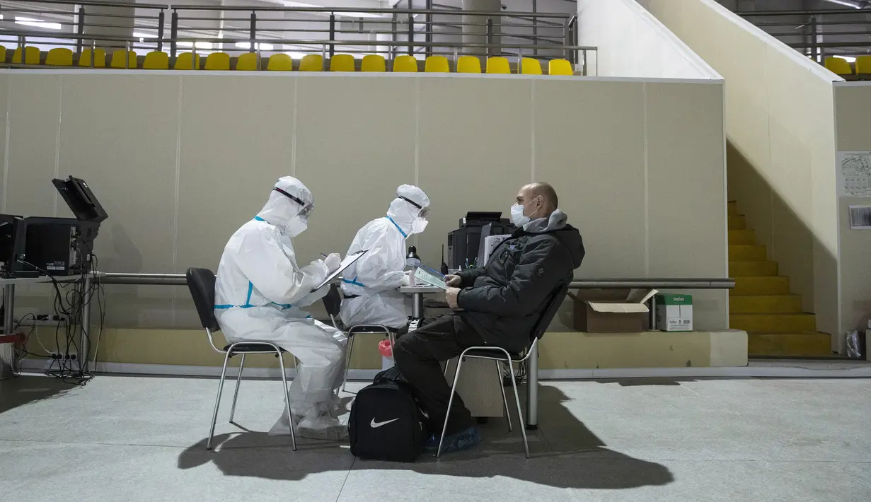 Petugas medis dengan alat pelindung diri mendaftarkan pasien baru di rumah sakit sementara virus corona COVID-19 di Istana Es Krylatskoe di Moskow, Rusia, Rabu (18/11/2020). Otoritas Moskow mengubah arena seluncur es menjadi rumah sakit sementara untuk menangani pasien COVID-19. (AP/Pavel Golovkin)