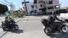 Orang-orang yang mengendarai sepeda motor melewati bangunan yang runtuh setelah gempa bumi di General Santos, Filipina, Senin 8 Juni 2026. (AP Photo)
