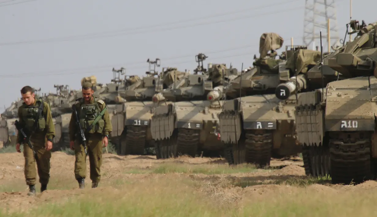 Tentara Israel berjalan melewati tank di dekat perbatasan Gaza-Israel, Jumat (19/10). Delegasi Mesir telah berkomunikasi dengan para pemimpin Israel untuk mengatasi ketegangan yang terjadi. (AP Photo/Ariel Schalit)