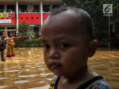 Anak-anak melintasi banjir yang melanda kawasan bantaran kali Cisadane, Tangerang, Jumat (26/4). Banjir kiriman setinggi 2 meter sempat melanda kawasan akibat curah hujan yang tinggi di bogor membuat derasnya air mengalir jauh sampai ke tempat ini. (Liputan6.com/Johan Tallo)