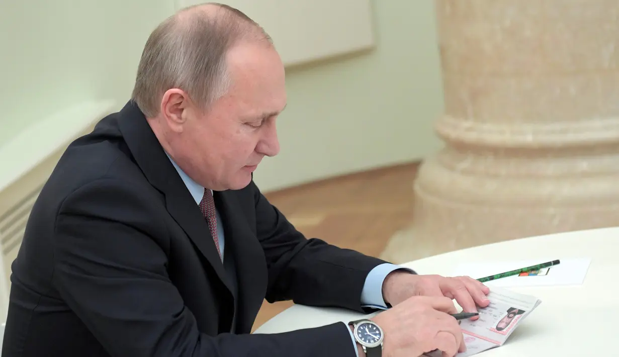 Presiden Rusia Vladimir Putin memeriksa paspor yang akan diberikan ke Steven Seagal di Kremlin di Moskow, Rusia, (25/11). Putin mengeluarkan keputusan memberi status kewarganegaraan bagi Steven Seagal. (Sputnik/Kremlin/Alexei Druzhinin via REUTERS)