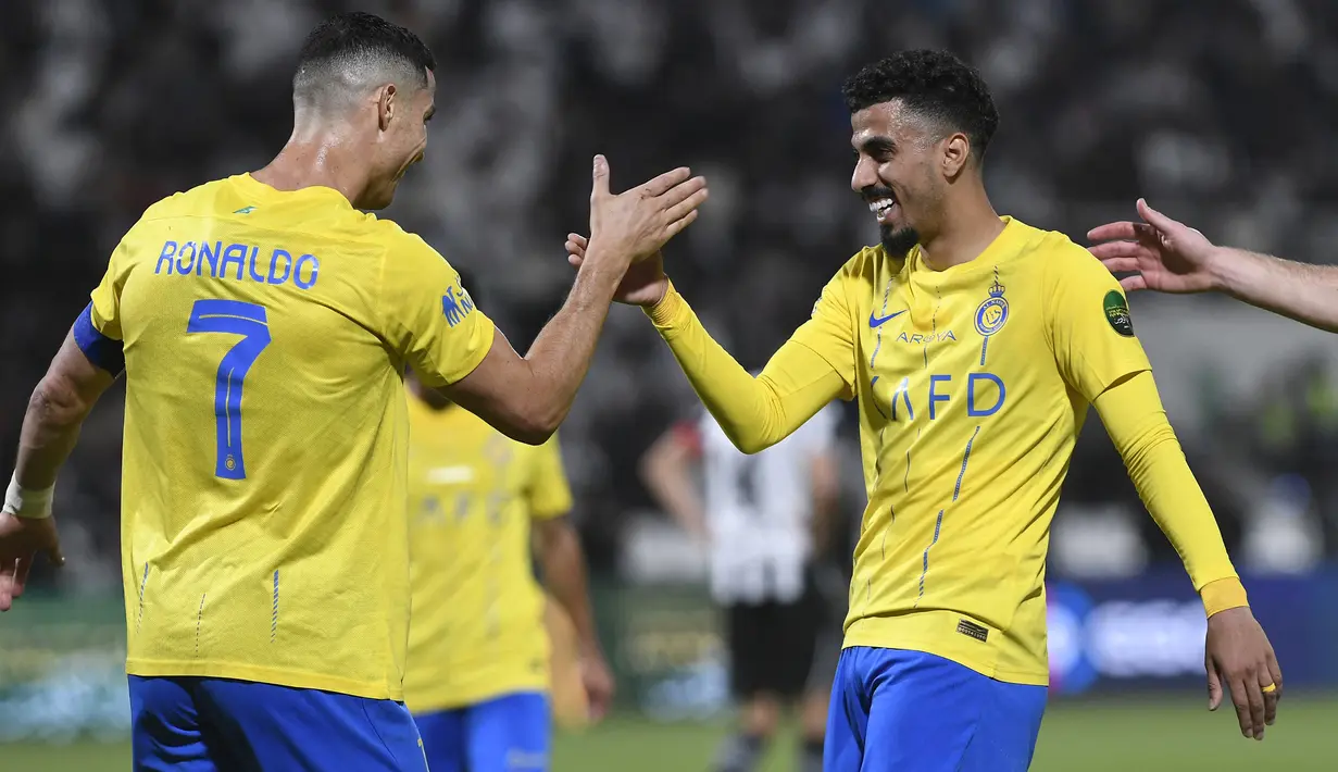 Pemain Al Nassr, Cristiano Ronaldo (kiri), melakukan selebrasi dengan Ali Lajami setelah dirinya mencetak gol ke gawang Al Shabab dalam laga perempat final King's Cup Arab Saudi 2023 yang digelar di Al Shabab Club Stadium, Selasa (12/12/2023) dini hari WIB. (AFP/Str)