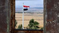Bendera Suriah berkibar di Kota Quneitra menghadap sisi Dataran Tinggi Golan yang dianeksasi Israel. (AP/Louiai Beshara)