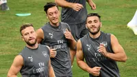 Gelandang Arsenal Mesut Ozil (tengah) bersama rekan-rekannya melakukan pemanasan saat mengikuti sesi latihan tim di Singapura (27/7). Arsenal akan bertanding melawan PSG pada International Champions Cup 28 Juli. (AFP Photo/Roslan Rahman)