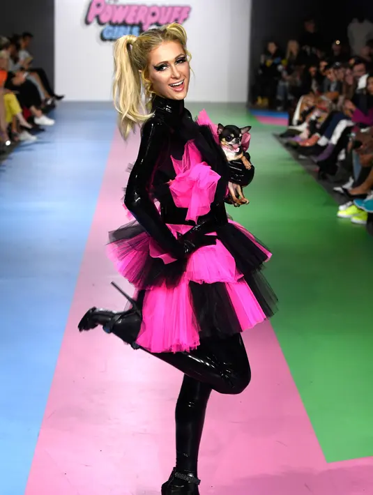 Paris Hilton membawa anjing saat tampil dalam Christian Cowan x The Powerpuff Girls Fashion Show, Los Angeles, AS, Jumat (8/3). Anjing tersebut terlihat seperti putri raja dengan simpul besar di tubuhnya. (Frazer Harrison/Getty Images North America/AFP)