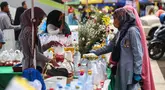 Pedagang bunga tabur melayani pembeli yang akan melakukan tradisi ziarah makam di Tempat Pemakaman Umum (TPU) Karet Bivak Jakarta, Minggu (3/3/2024). (Liputan6.com/Angga Yuniar)