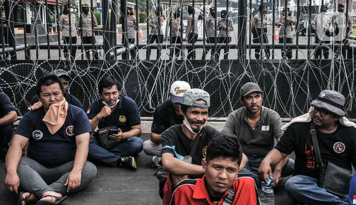 Pengemudi taksi dan ojek online saat menggelar aksi di depan Gedung DPR RI, Jakarta, Rabu (21/9/2022). Puluhan massa tersebut menuntut pemerintah membuat payung hukum bagi mitra pengemudi online, menaikkan tarif dasar, menyetarakan potongan menjadi 10 persen, dan meminta subsidi asuransi kesehatan. (merdeka.com/Iqbal S. Nugroho)