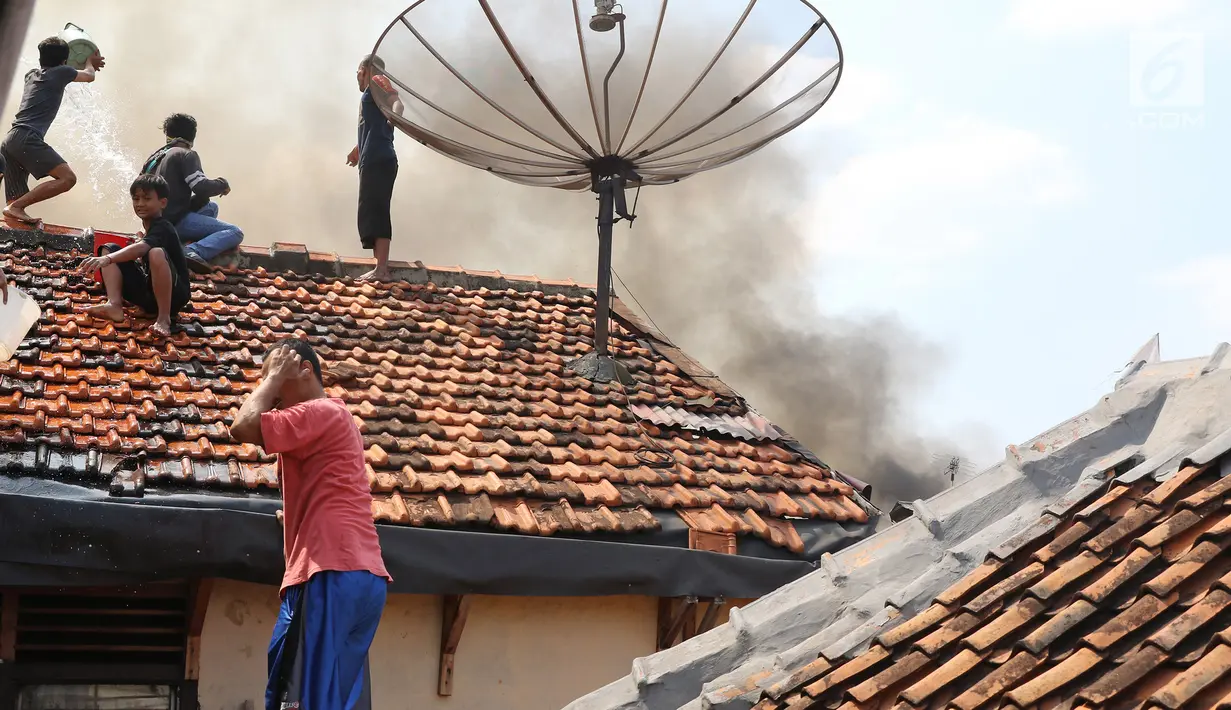 Sejumlah warga memadamkan api membakar pemukiman padat penduduk di kawasan Manggarai, Jakarta, Rabu (10/7/2019). Sebanyak 27 Unit mobil pemadam kebakaran diterjunkan untuk memadamkan api yang melanda pemukiman di dekat Stasiun Manggarai tersebut. (Liputan6.com/Herman Zakharia)