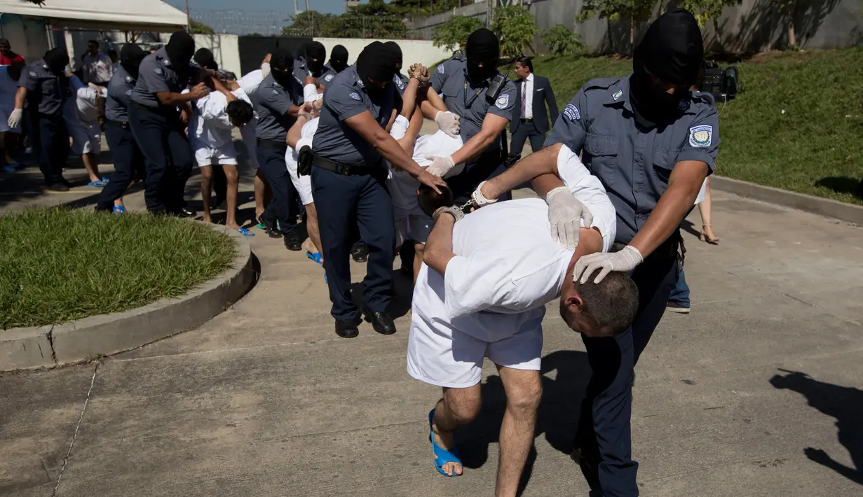 Petugas kepolisian menggelandang anggota geng Mara Salvatrucha di Zacatecoluca, El Salvador (31/1). 32 anggota geng tersebut dituduh membunuh pasukan keamanan dalam beberapa bulan terakhir. (AP Photo/Moises Castillo)