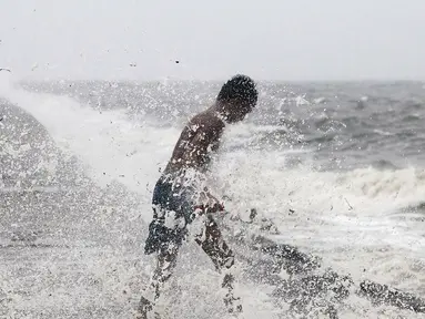 Seorang anak laki-laki mencari botol-botol plastik untuk didaur ulang ditengah deburan gelombang akibat Topan Koppu di Teluk Manila, Minggu (18/10). Topan Koppu melanda Filipina timur laut dan merusak rumah-rumah. (REUTERS/Romeo Ranoco)