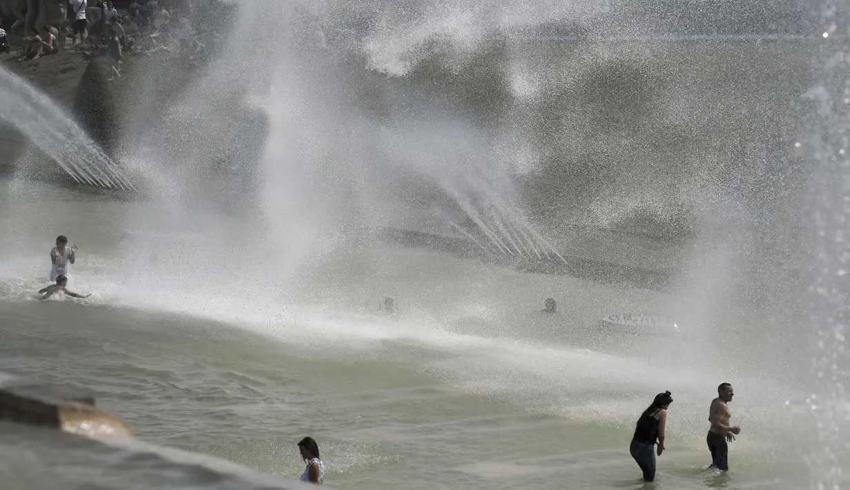 Sejumlah warga bermain di kolam air mancur di Trocadero Fountains dekat Menara Eiffel, Paris (22/7/2019). Warga Paris bersiap menghadapi suhu terpanas pada minggu ini ketika gelombang panas akan melanda ke Eropa utara. (AFP Photo/Alain Jocard)