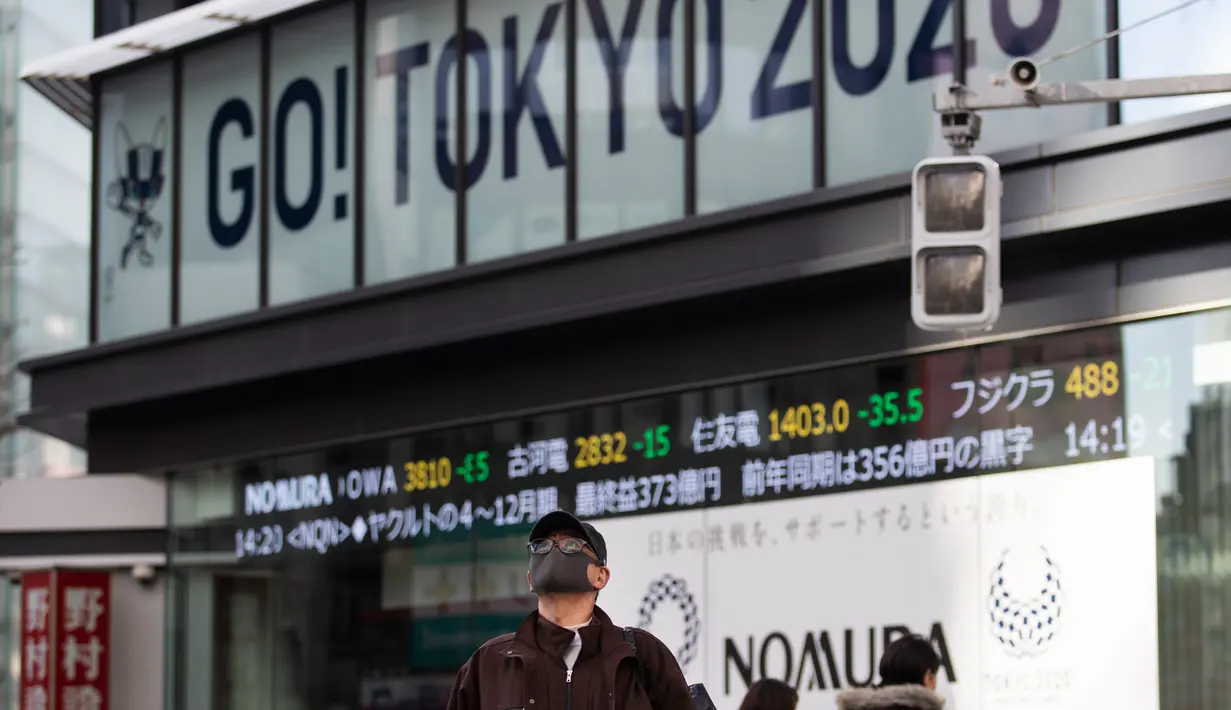Seorang pria yang mengenakan masker berjalan dekat papan bertema Olimpiade yang disponsori perusahaan sekuritas di Tokyo, Jepang, Jumat (29/1/2021). Olimpiade 2020 Tokyo yang ditunda terkait pandemi virus corona Covid-19 dijadwalkan ulang untuk diadakan pada musim panas ini. (AP Photo/Hiro Komae)