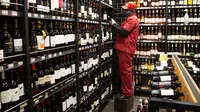 Seorang pria mengisi rak dengan botol anggur di toko minuman keras ketika Afrika Selatan mencabut larangan penjualan alkohol dan rokok di Johannesburg, Selasa (18/8/2020). Pembelian alkohol dan rokok dilarang ketika Afsel memberlakukan lockdown ketat pada 27 Maret 2020. (AP Photo/Denis Farrell)